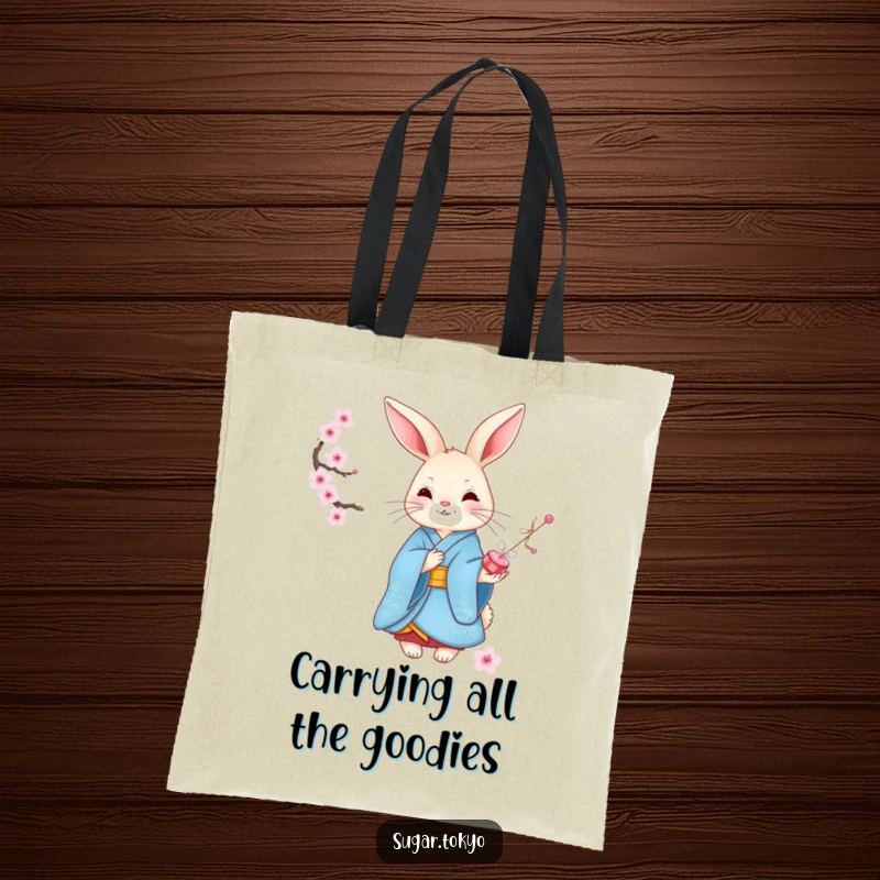 Funny graceful rabbit in an elegant blue kimono offering cherry blossom candies on a durable tote bag, showcasing refined and funny appeal.